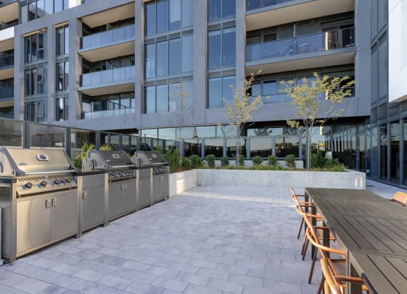 an outdoor patio with barbecue grills and a wooden table and chairs