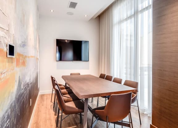 a conference room with a table and chairs and a television
