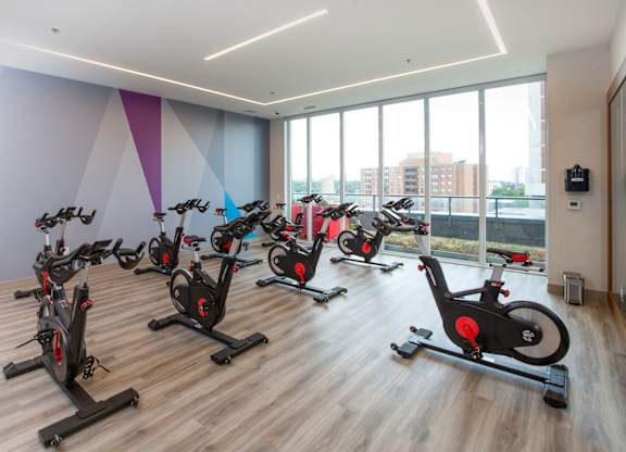a spin class room with exercise bikes in front of a wall of windows