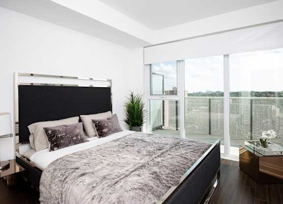A bedroom with a large bed and a view of the outside through the window.