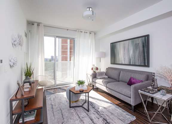 A living room with a grey couch, a coffee table, and a painting on the wall.