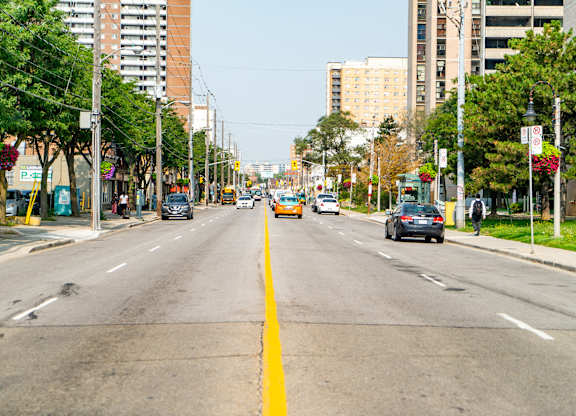 A city street with cars and a yellow line in the middle.