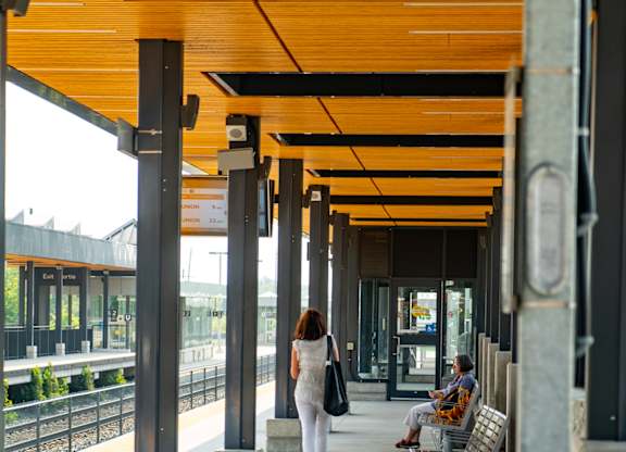 A woman in a white dress is walking on a platform with a train in the background.