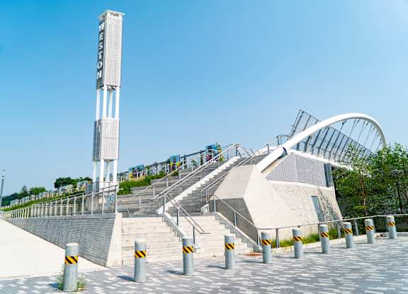 A tall white tower with a sign on it stands next to a set of stairs with a metal railing.