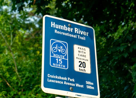 A sign for the Humber River Regional Trail is shown in front of some trees.