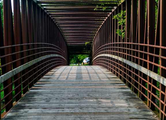 A bridge with a metal railing and wooden planks.