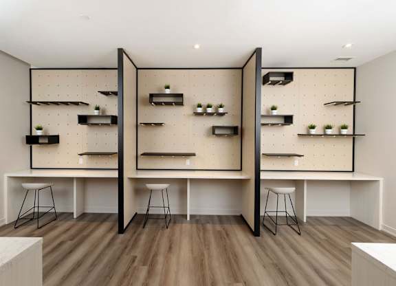 A room with a white table and black stools.