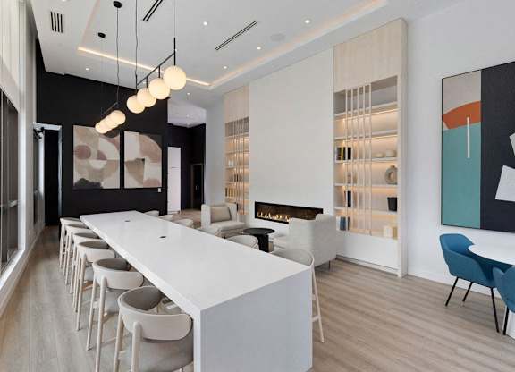 A long white table with chairs on either side is in the middle of a room.