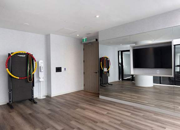 A room with a wooden floor and a black TV on a white stand.