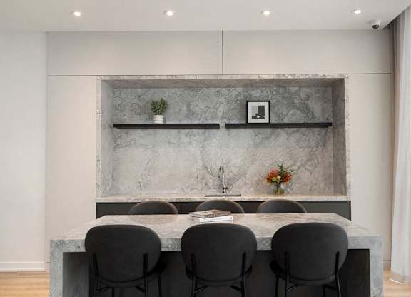 A modern kitchen with a marble backsplash and grey countertop.