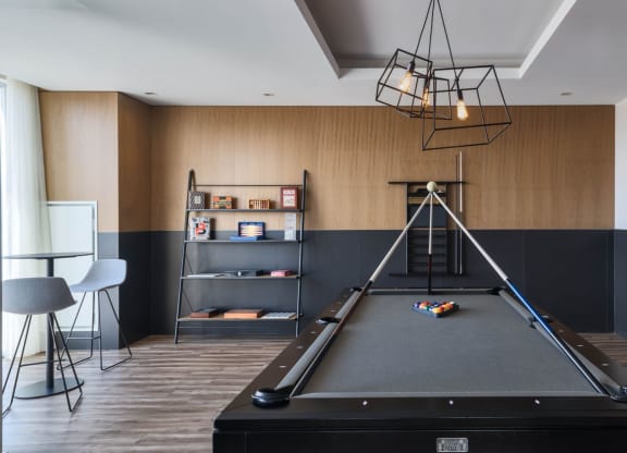 a games room with a pool table and a modern light fixture