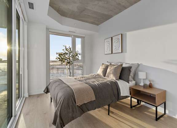 A bedroom with a large bed and a small table by the window.