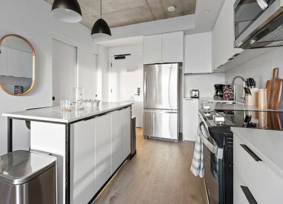A modern kitchen with a stainless steel refrigerator and wooden floors.