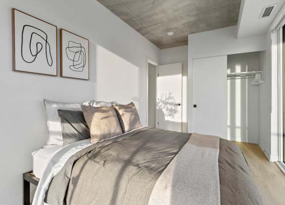 A bedroom with a large bed and two abstract art pieces on the wall.