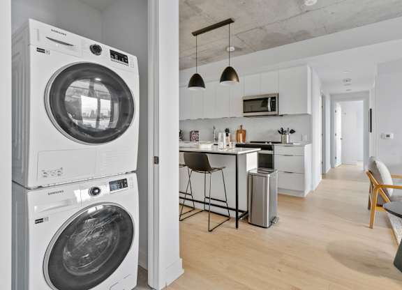 A white washing machine is stacked on top of another in a modern kitchen.