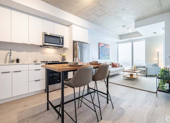 A modern kitchen with white cabinets and a dining table with chairs.