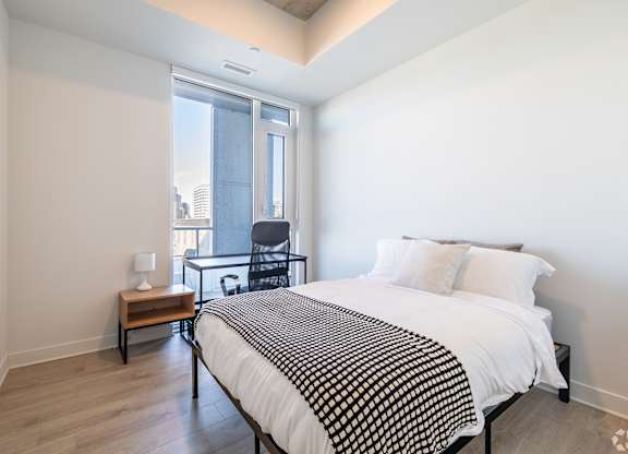 A bedroom with a bed, chair, and window.