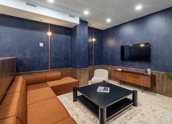 A modern living room with a brown sofa, a black coffee table, and a flat-screen TV mounted on the wall.