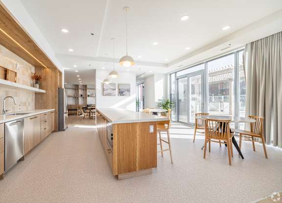 A modern kitchen with wooden cabinets and a dining table.
