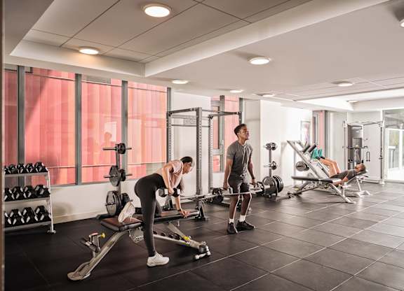 A man is working out in a gym with a woman.