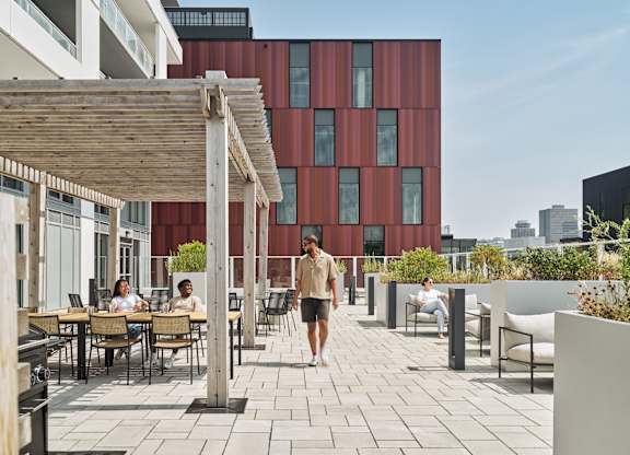 A woman walks down a patio with tables and chairs.