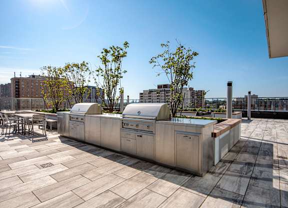 A rooftop patio with a grill and seating area.