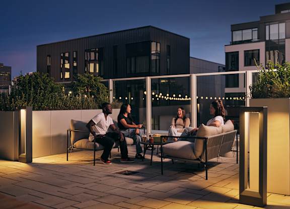 Four people are sitting on a patio at night.