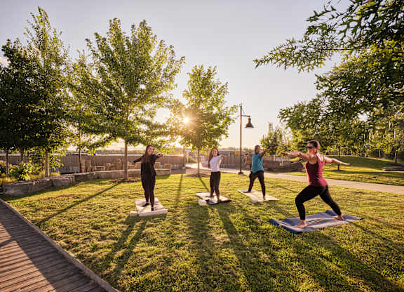 Four people practicing yoga in a park.