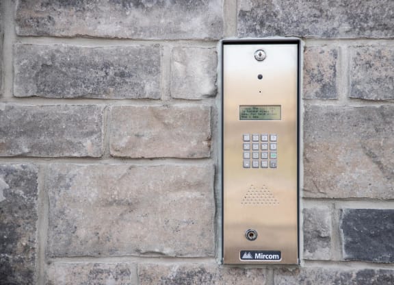 a stainless steel elevator control panel on a brick wall