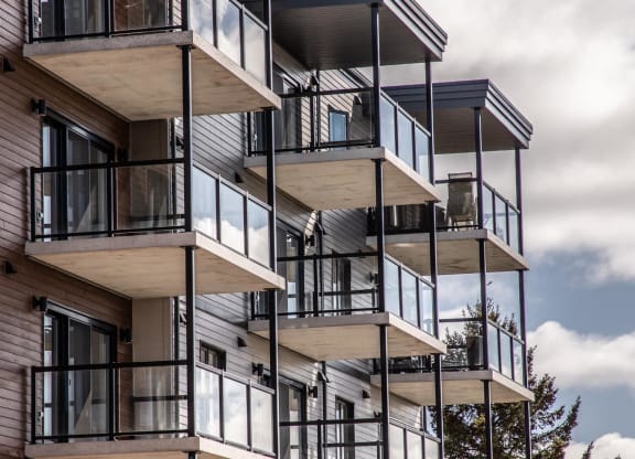a tall apartment building with balconies and a cloudy sky
