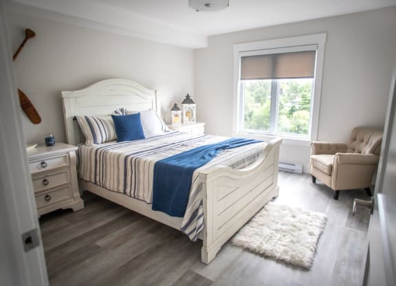 a bedroom with a bed and a chair and a window