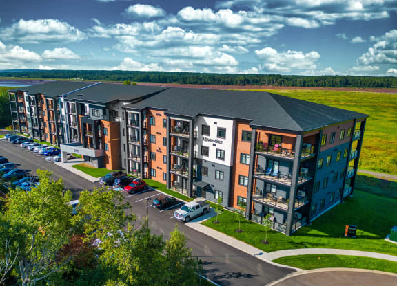 an aerial view of an apartment building with cars parked outside