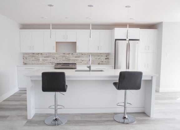 a white kitchen with two bar stools