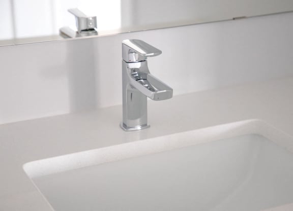 a white sink in a bathroom with a silver faucet