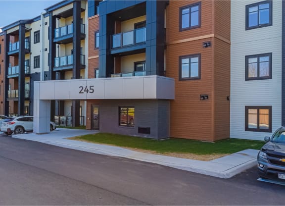 modern apartment building on the corner of a street with cars parked