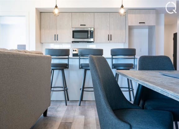 a kitchen with bar stools and a counter with chairs