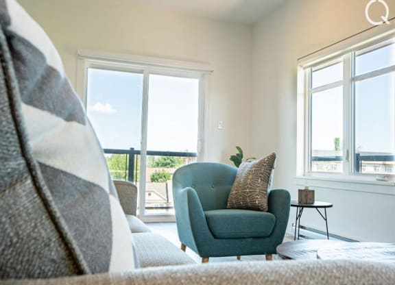 a living room with a couch and a chair and two windows