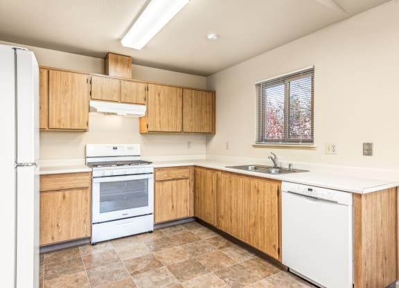 Kitchen with white appliances and wooden cabinets at Meadowview Apartments, Santa Rosa, CA