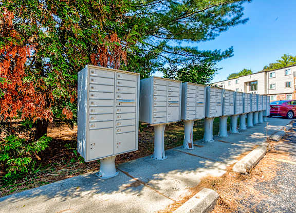 A row of mailboxes are lined up on a sidewalk.