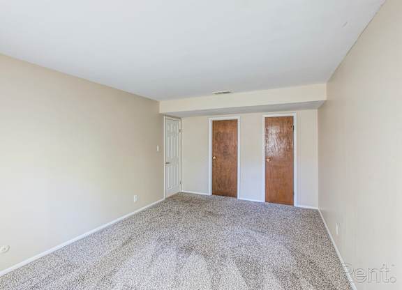 A room with a carpeted floor and two wooden doors.
