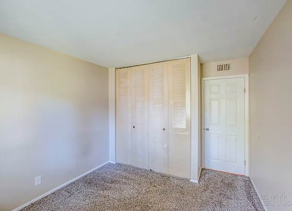A bedroom with a carpeted floor and a white door.