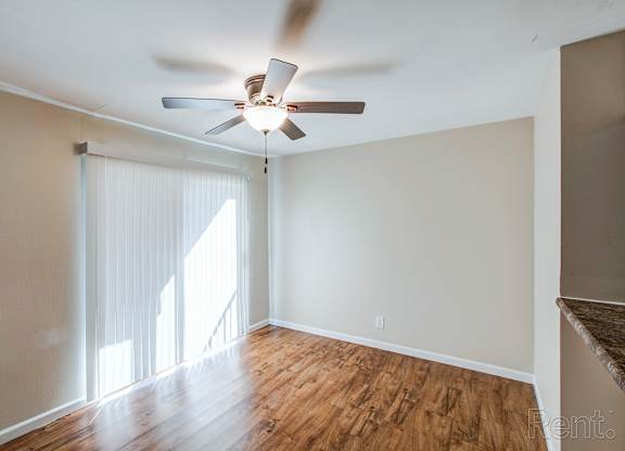 A room with a ceiling fan and wooden flooring.