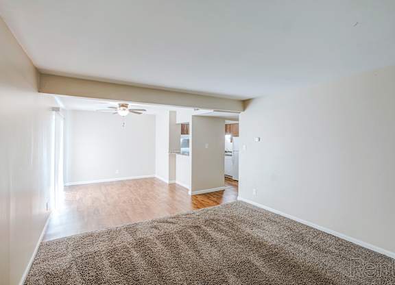 A room with a carpet on the floor and a ceiling fan.