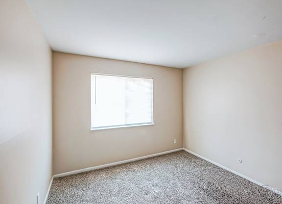 A room with a window and carpeted floor.
