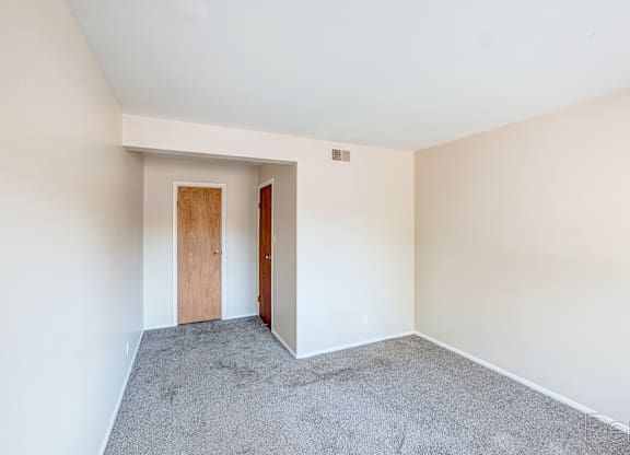 A room with a carpeted floor and a wooden door.