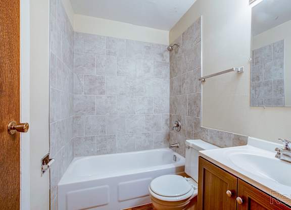A bathroom with a white tub, toilet, and sink.