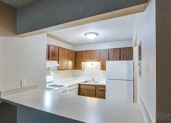 A kitchen with white appliances and wooden cabinets.