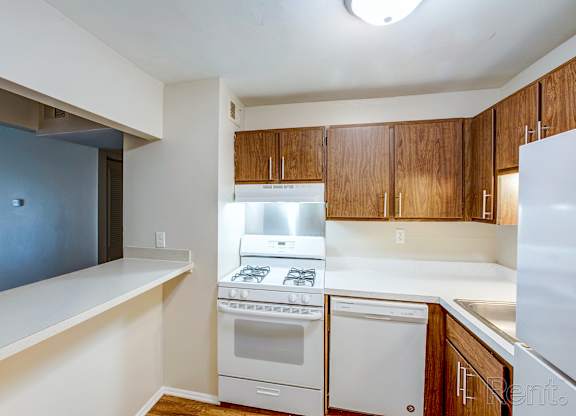 A kitchen with white appliances and wooden cabinets.