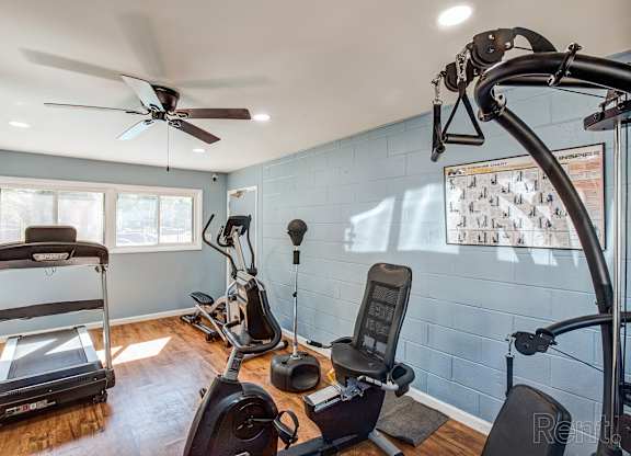 A home gym with a treadmill, exercise bike, and other equipment.