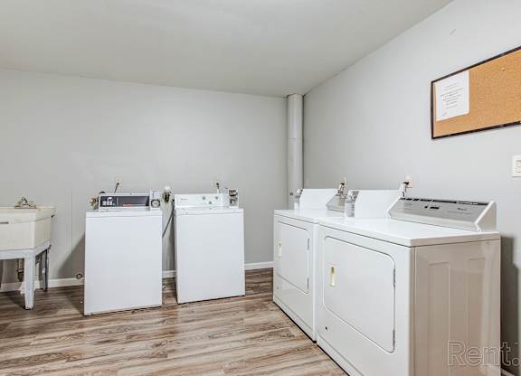 A laundry room with a washer, dryer, ironing board, and sink.